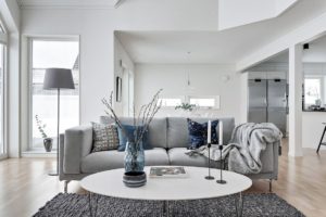 Foto på grå soffa och vitt soffbord med blå vas