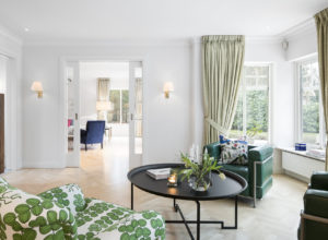 grön fåtölj med stort brickbord och gröna gardiner