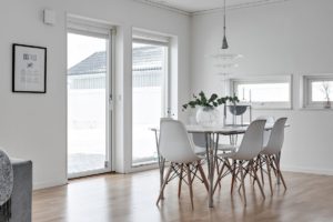 foto på ljust rum med stort matbord med vita moderna stolar